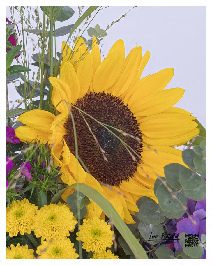 Die leuchtende Sonnenblume bringt strahlende Wärme in das Trauergesteck, harmonisch ergänzt durch gelbe Santini und frisches Eukalyptusgrün