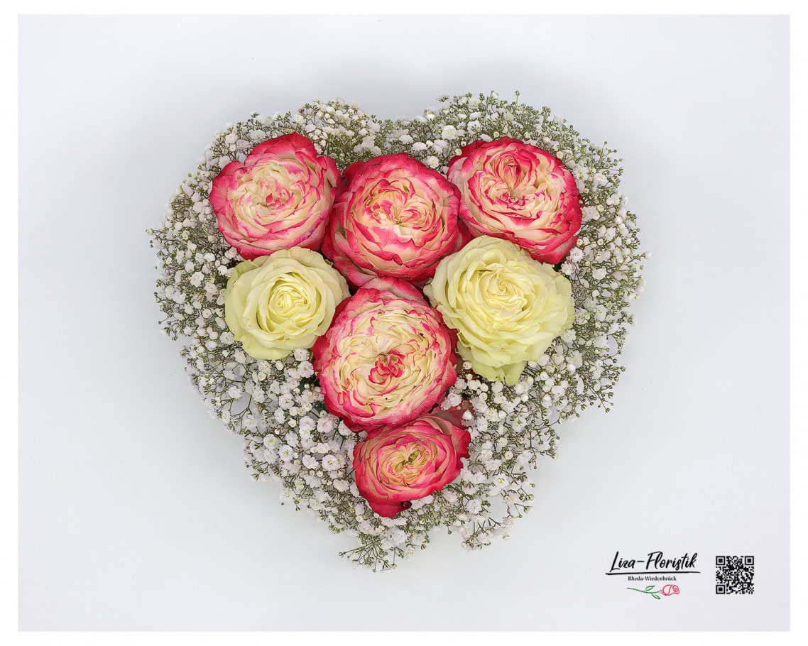 Herzförmiges Trauergesteck mit edlen Rosen und feinem Schleierkraut, das mit seiner sanften Symbolik liebevoll Abschied nimmt und Trost spendet.