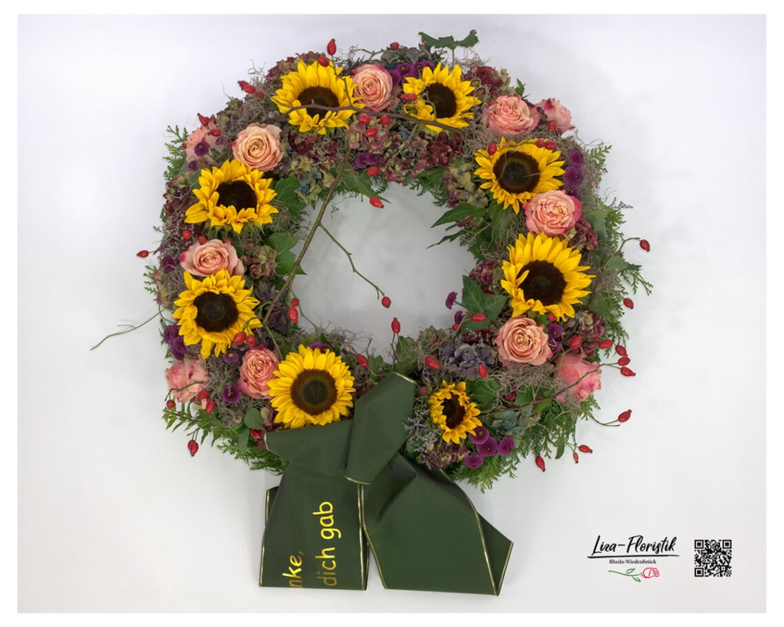 Blumenkranz zur Beerdigung mit Sonnenblumen, Rosen, Hortensien, Hagebutten und violetten Chrysanthemen – handgebundene Trauerfloristik für einen würdevollen Abschied.