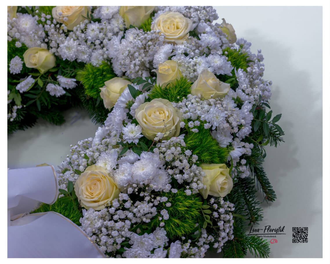 Zwischen den creme-weißen Ecuador-Rosen und dem fedrigen Schleierkraut öffnen sich die ersten Chrysanthemenblüten – ein Zusammenspiel aus Form und Zartheit, das dem Kranz seine Tiefe gibt